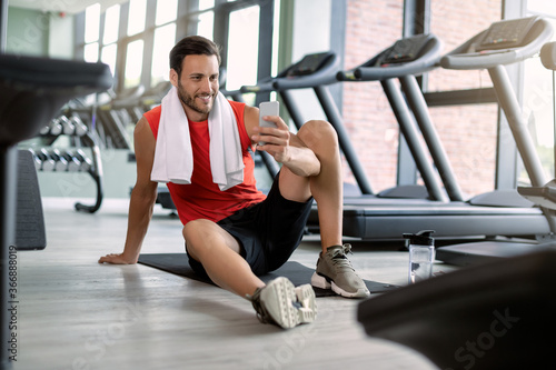 Wallpaper Mural Happy athletic man text messaging on cell phone in health club. Torontodigital.ca