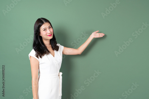 Young asian woman with hand presenting on side