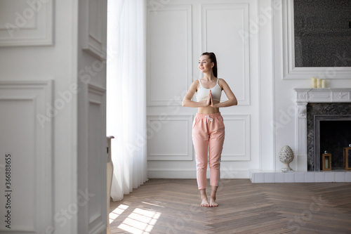 Young happy woman doing relaxing exercises at home in the morning. photo