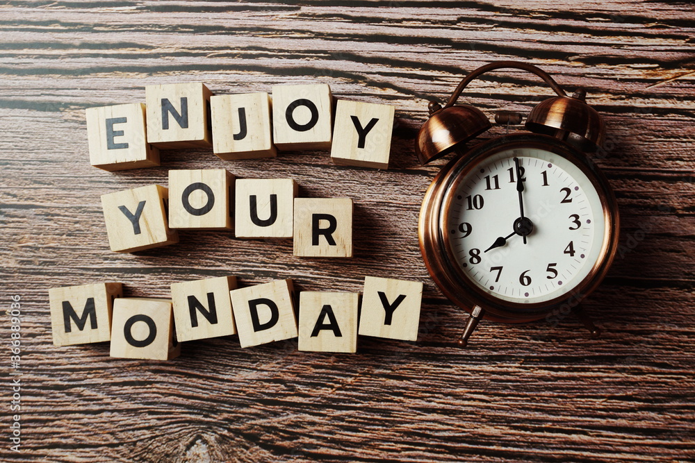 Enjoy Your Monday alphabet letter with alarm clock on wooden background Enjoy Your Monday alphabet letter with alarm clock on wooden background