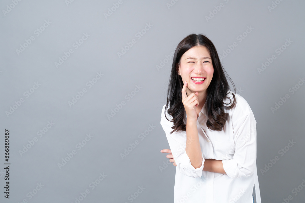 Young and beautiful asian woman in white shirt on grey background