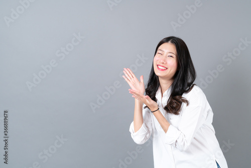Young and beautiful asian woman in white shirt on grey background