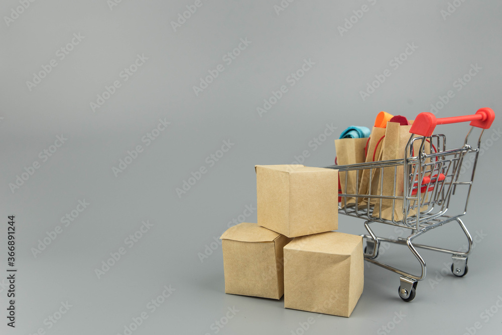 Shopping cart with purchases - packages and boxes on trendy gray background with copy space isolated. Online shopping and sale concept.