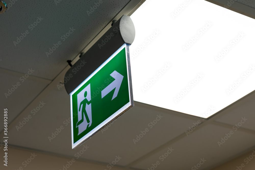 Green fire escape sign hang on the ceiling in the office Green fire escape sign hang on the ceiling in the office