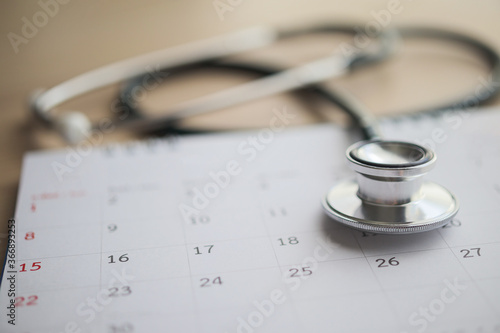 Stethoscope with calendar page date on wood table background doctor appointment medical concept