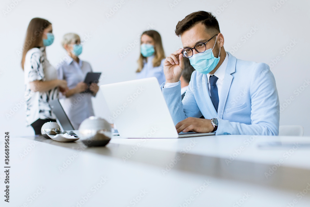 Young business man with medical protective mask works on a laptop Young business man with medical protective mask works on a laptop