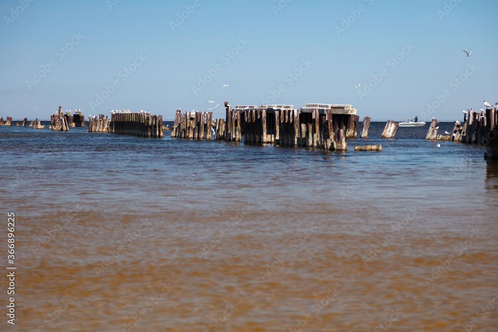 An old abandoned pier in the sea. Sunny summer day. Seagulls