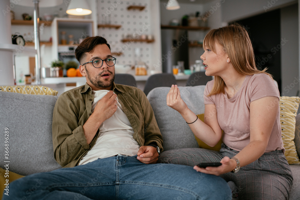 Boyfriend and girlfriend are arguing on the couch. Angry girlfriend is yelling at her boyfriend.. Boyfriend and girlfriend are arguing on the couch. Angry girlfriend is yelling at her boyfriend..