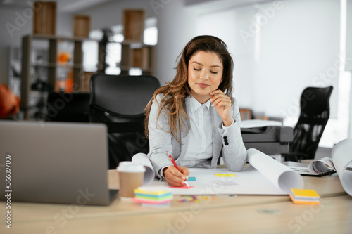 Beautiful young businesswoman working on projects. Businesswoman in suit working in the office.	