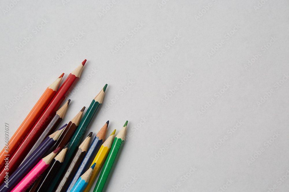 Several colored pencils of various shades lie on a white background, macro photography. Several colored pencils of various shades lie on a white background, macro photography.