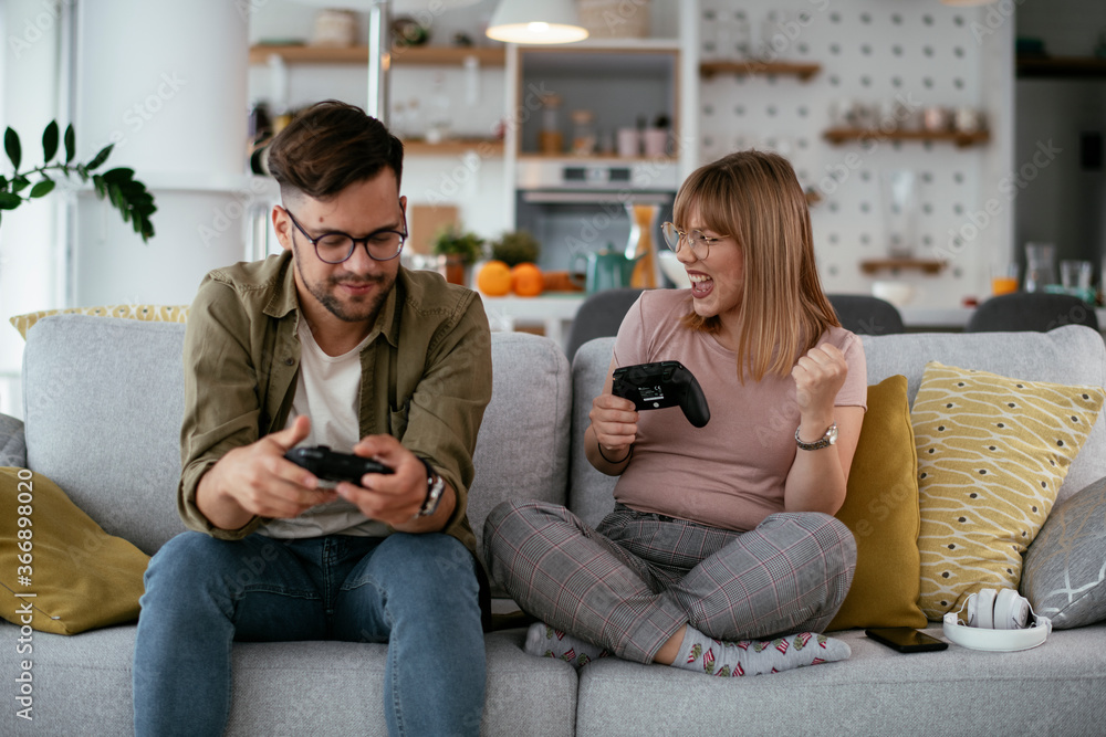 Husband and wife playing video game with joysticks in living room. Loving couple are playing video games at home. Husband and wife playing video game with joysticks in living room. Loving couple are playing video games at home.