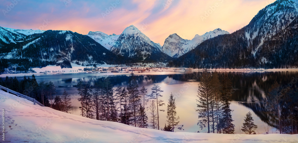 dreamy sunset mood at lake Achensee, view to pertisau tourist resort and snowy alps