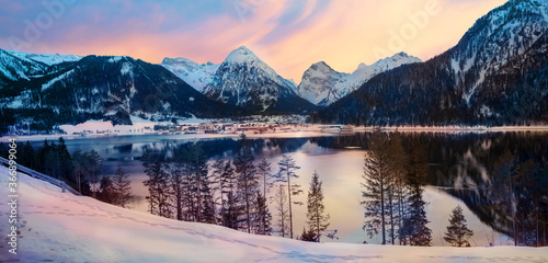 dreamy sunset mood at lake Achensee, view to pertisau tourist resort and snowy alps