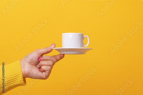 coffee cup in hand over yellow background