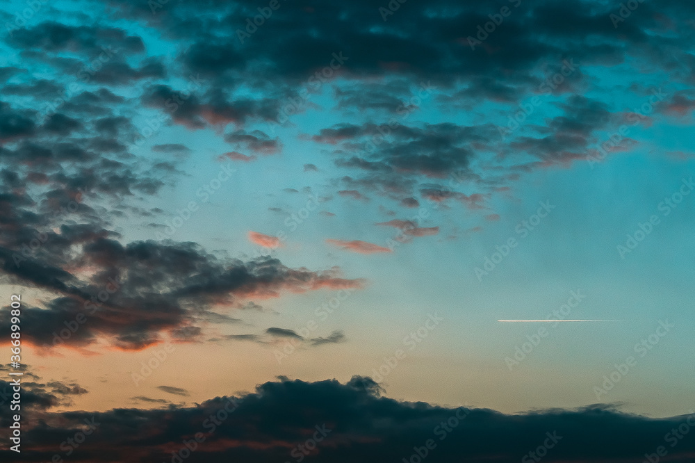 Colorful sunset cloudscape with an airplane contrail Colorful sunset cloudscape with an airplane contrail