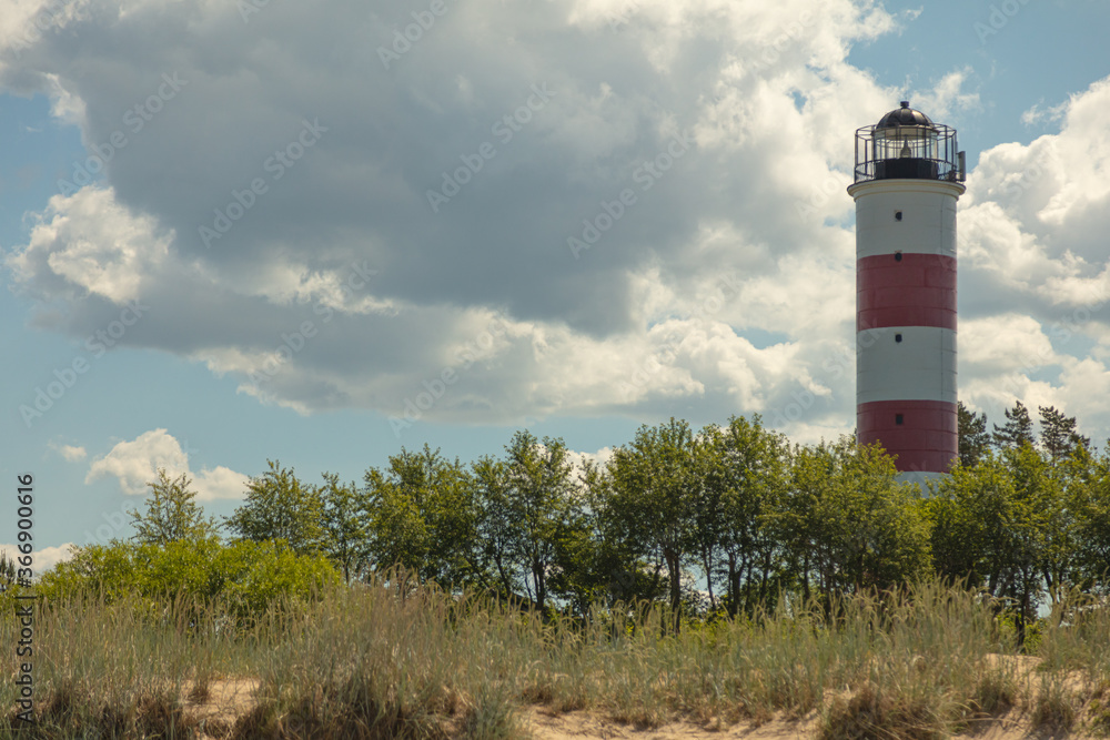 Lighthouse in Narva-Jõesuu on a sand dune with white clouds. Baltic