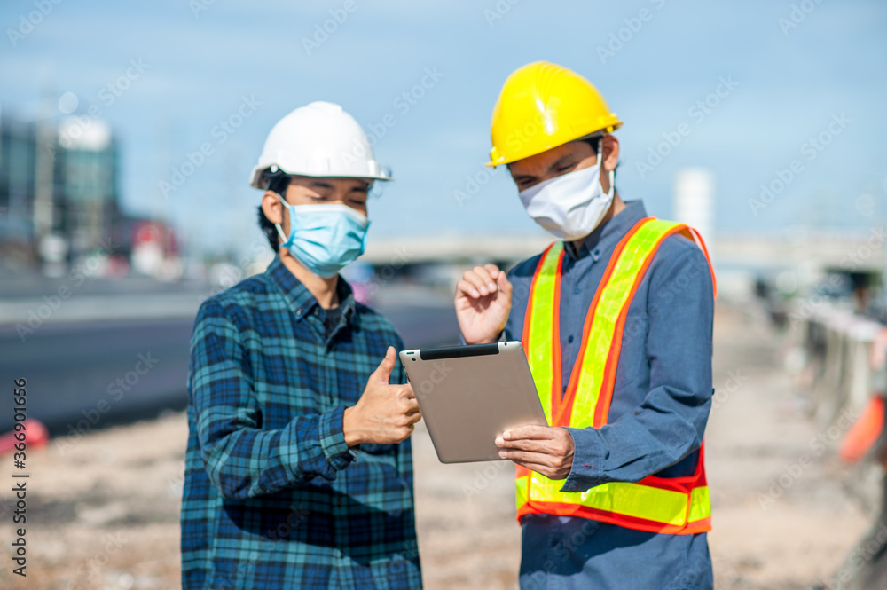 Two engineer talking project construction on site,Man two people a wearing face mask working meeting on tablet at site work place Two engineer talking project construction on site,Man two people a wearing face mask working meeting on tablet at site work place