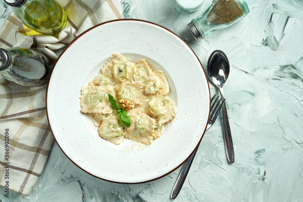 Italian traditional ravioli with minced meat in a creamy nut sauce in a white plate