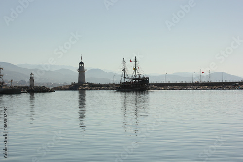 Alanya, TURKEY - August 10, 2013: Travel to Turkey. The waves of the Mediterranean Sea. Water surface. Port. Ships on the water. Boats at sea. Yachts and other water transport. Lighthouse. Mountains i