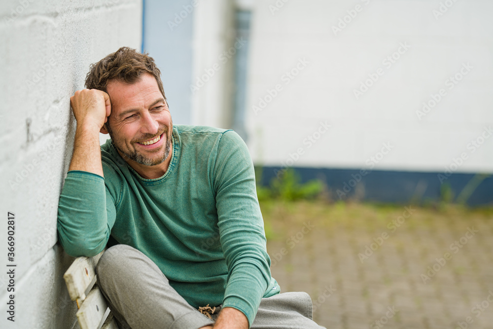 sexy Mann sitzt entspannt auf einer Bank und lacht sexy Mann sitzt entspannt auf einer Bank und lacht