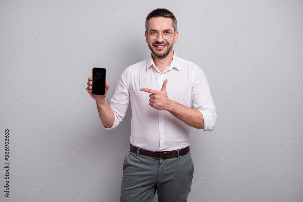 Portrait of his he nice attractive cheerful content classy mature man holding in hands showing cell ad credit loan cool decision isolated over light gray pastel color background Portrait of his he nice attractive cheerful content classy mature man holding in hands showing cell ad credit loan cool decision isolated over light gray pastel color background
