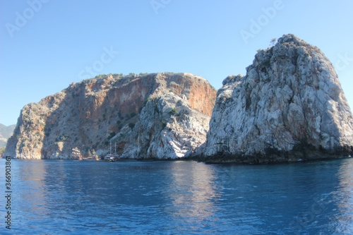 Alanya, TURKEY - August 10, 2013: Travel to Turkey. The waves of the Mediterranean Sea. Water surface. Mountains and hills on the coast of Turkey. Port. Green hills. © andreswestrum