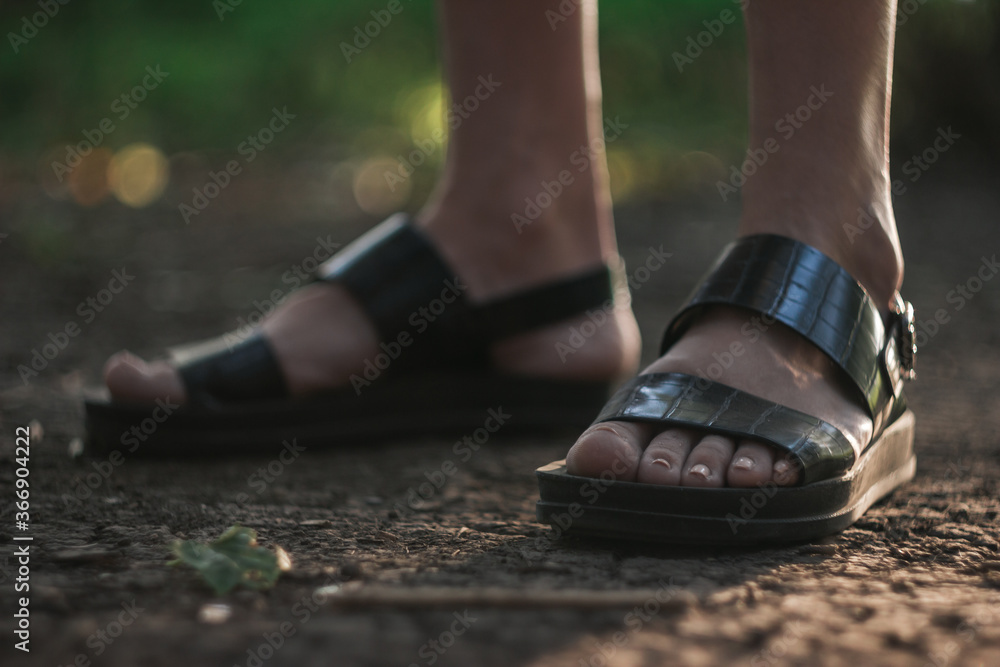 a girl walks through the forest alone, female legs close-up. Young girl in sandals