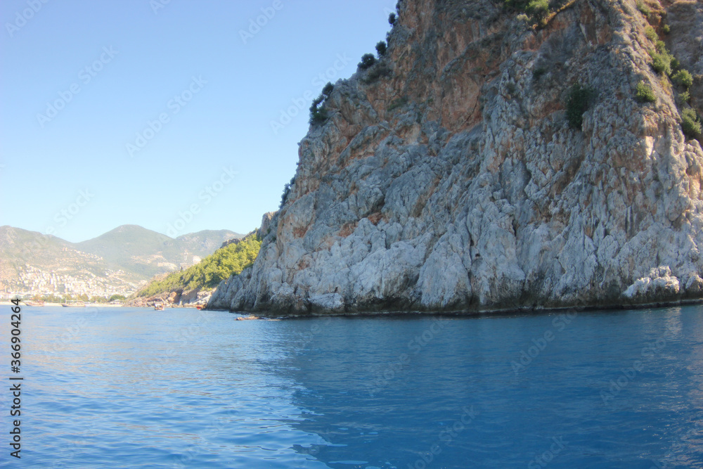 Alanya, TURKEY - August 10, 2013: Travel to Turkey. The waves of the Mediterranean Sea. Water surface. Mountains and hills on the coast of Turkey. Port. Green hills.