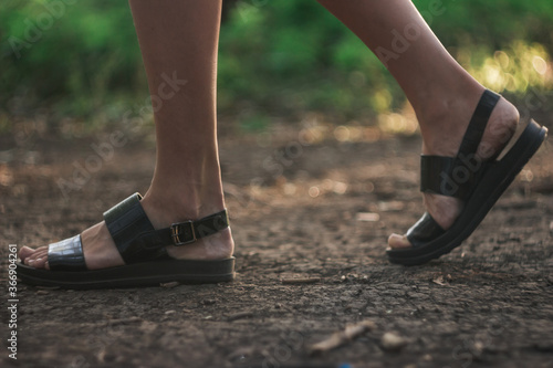 a girl walks through the forest alone, female legs close-up. Young girl in sandals