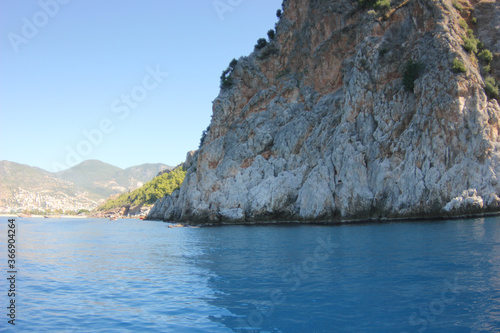 Alanya, TURKEY - August 10, 2013: Travel to Turkey. The waves of the Mediterranean Sea. Water surface. Mountains and hills on the coast of Turkey. Port. Green hills.