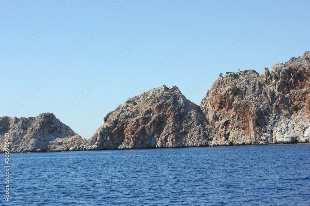 Alanya, TURKEY - August 10, 2013: Travel to Turkey. The waves of the Mediterranean Sea. Water surface. Mountains and hills on the coast of Turkey. Green hills.