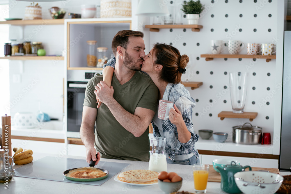 Young couple making pancakes together at home. Loving couple having fun while cooking. Young couple making pancakes together at home. Loving couple having fun while cooking.