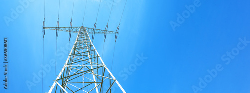Electricity background banner panorama - Voltage power lines / high voltage electric transmission tower with blue sky and shining sun