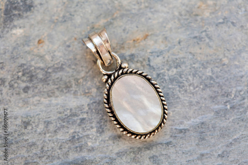 Natural shell pendant in silver metal decorative oval on natural backhround