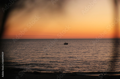 Parasailing. Active type of recreation at the sea. Parachute flights behind a boat at sunset. © andreswestrum