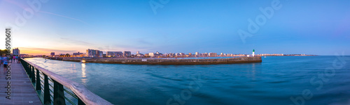 Panoramic view of entrance of Les Sables D'Olonne harbor taken from La Chaume with the seaside resort of Les Sables D'Olonne in the background, with its piers and lighthouse at sunset, Vendee, France