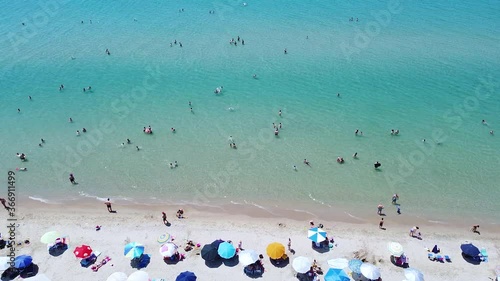 Sunny tourists weekend day on the beach. Busy day on the beach with people enjoying in sun and sea. Aerial view 