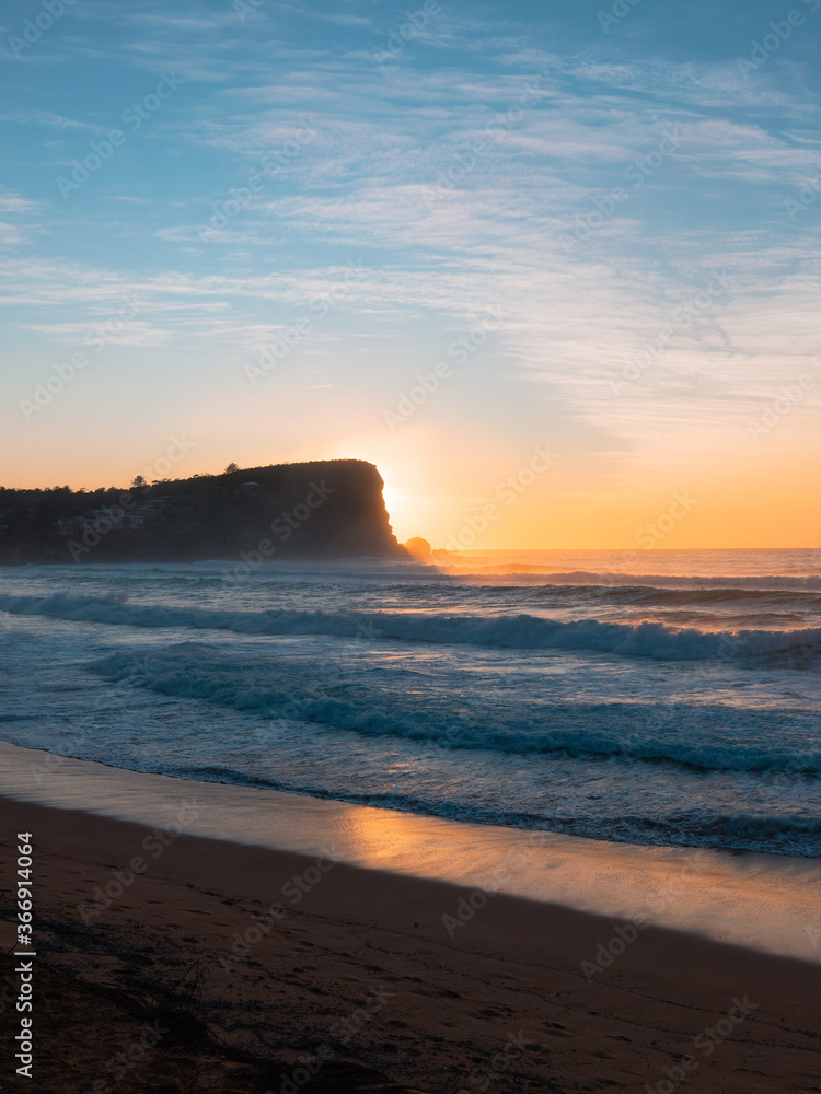 Beach with sunrise light behind the cliff.