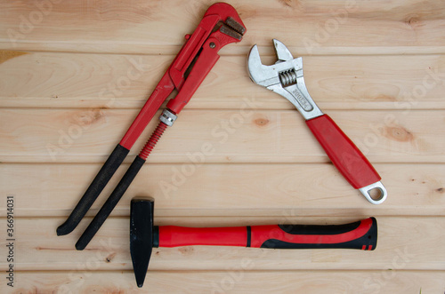 Tools for plumbing on a wooden background. Red wrench and hammer. Plumbing tools background. 