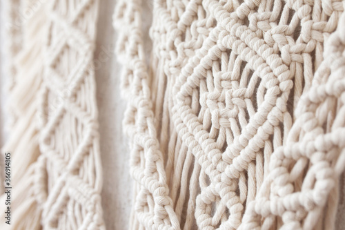 Close-up of hand made macrame texture pattern.  ECO friendly modern knitting DIY natural decoration concept  in the interior. Flat lay. Handmade macrame 100% cotton. Details close up. Female hobby.