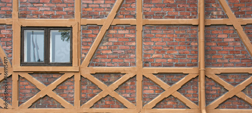 Pattern of traditional half-timbered house wall with red brick and window