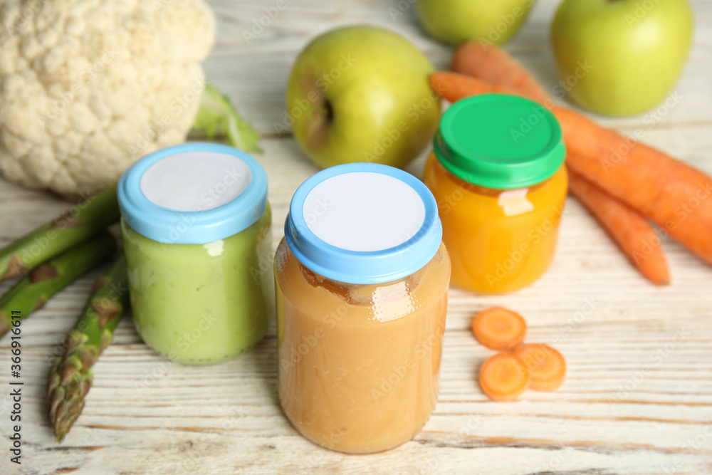 Jars with baby food and fresh ingredients on white wooden table Jars with baby food and fresh ingredients on white wooden table