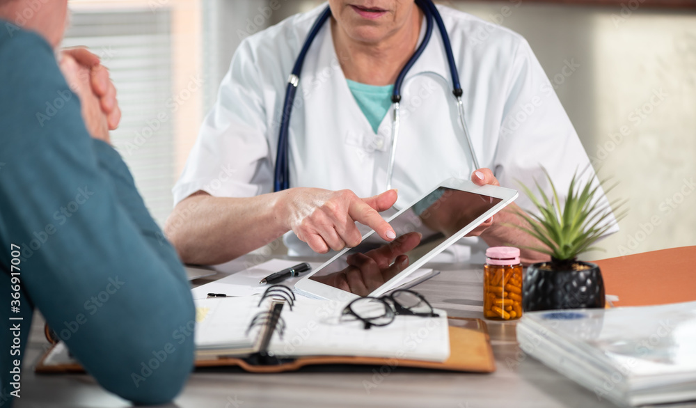 Female doctor showing reports on digital tablet to her patient Female doctor showing reports on digital tablet to her patient