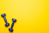 top view of blue dumbbells on yellow background