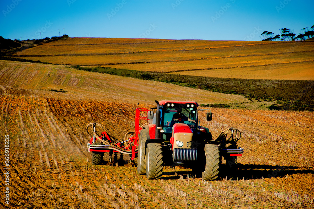 Obraz premium Farm Tractor preparing fields for plating canola
