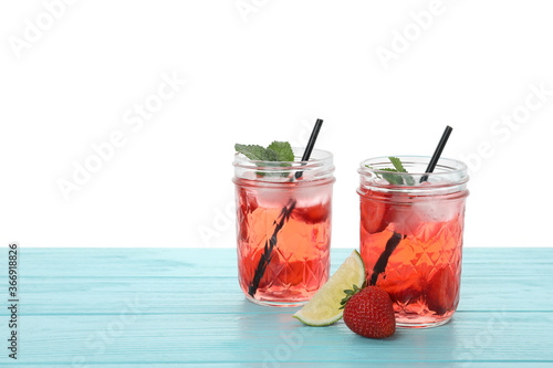 Refreshing drink with strawberry and lime on light blue wooden table