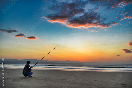 Fisherman on Lookout Beach with sunrise in Plettenberg Bay 