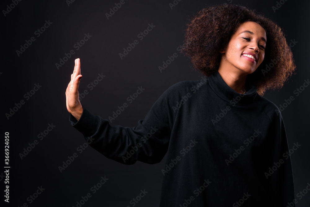 Young beautiful African woman with Afro hair against black background Young beautiful African woman with Afro hair against black background