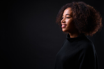 Young beautiful African woman with Afro hair against black background