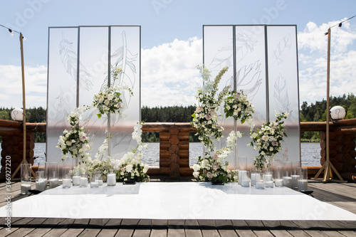 Wedding ceremony with white transparent screens and fresh white flowers and candles